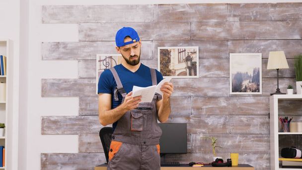 "Male worker in coveralls being confused while reading intructions" - 写真・画像