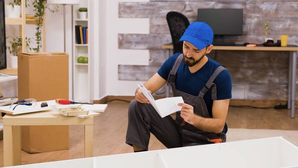 Збентежений працівник збірки меблів під час читання інструкцій
 - Фото, зображення