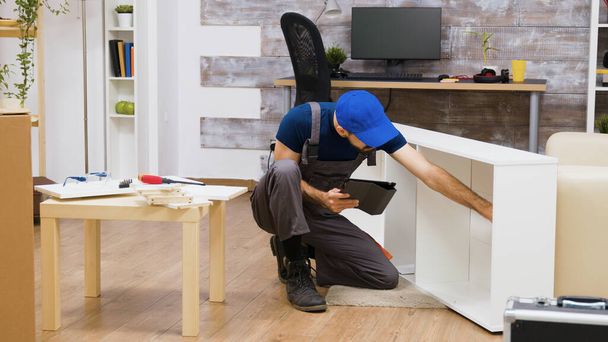 Trabalhador masculino usando tecnologia moderna para montagem de móveis
 - Foto, Imagem