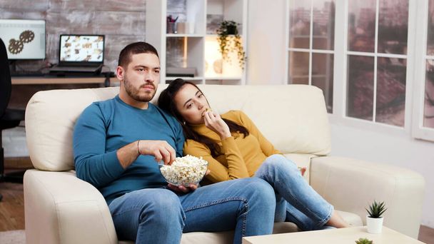 "Valkoihoinen pari rentouttava television katselu olohuoneessa
" - Valokuva, kuva