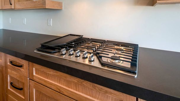 Panoráma Modern kézműves konyhapult gáztűzhellyel, grillezési lehetőséggel és egyedi szellőzőnyílással. Konyha fekete pult természetes fa fiókok és szekrények alatt a lebegő polcok és szekrény. - Fotó, kép