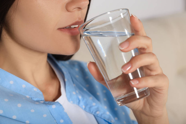 Young woman drinking water indoors, closeup. Refreshing drink - Photo, image
