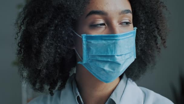 Hasta kadın öğrenci kıvırcık Afrikalı hasta. Coronavirüs enfeksiyonundan korunmak için tıbbi maske takıyor. Ağız ve burun tıkanıklığını her gün kapatıyor. - Video, Çekim