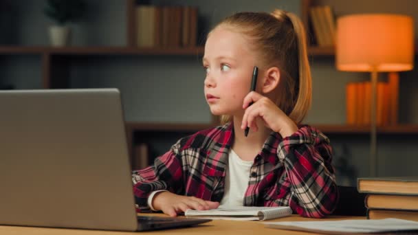 Luova lapsi junior school tyttö huomaavainen oppilas lapsi tekee kotitehtäviä katsella koulutusvideo verkossa käyttää tietokonelaite opiskeluun keksiä super idea tuntuu oivalluksia luoda vastaus matematiikan tehtävä - Materiaali, video