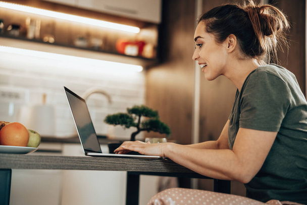 Bir kadının sabah evde dizüstü bilgisayarla internette sörf yaparken görüntüsü.. - Fotoğraf, Görsel