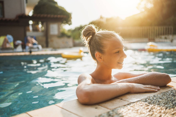 Linda chica adolescente sonriente disfrutando de unas vacaciones de verano en la piscina. - Foto, imagen