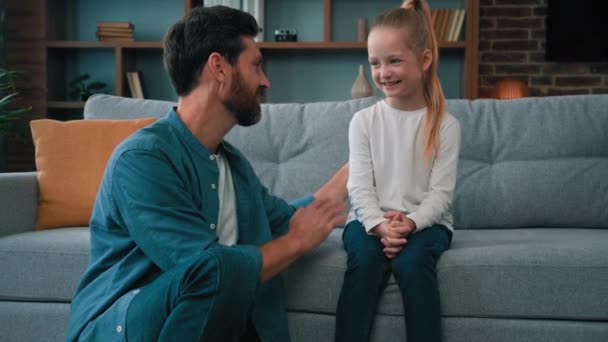 Szczęśliwy tata psycholog siedzieć na podłodze w domu rozmawiając z cute córka dziecko kochający rodzic dając przybić piątkę do dość mała dziewczynka zachęcić dobre zachowanie kaukaska rodzina zabawy bawić się razem - Materiał filmowy, wideo