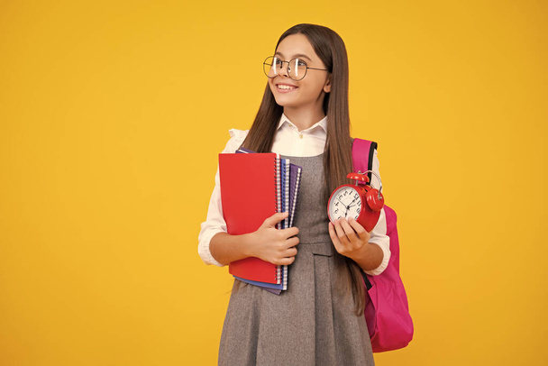 School teen girl checking time. Schoolgirl with clock alarm. School time. Happy face, positive and smiling emotions of teenager schoolgirl - Photo, Image