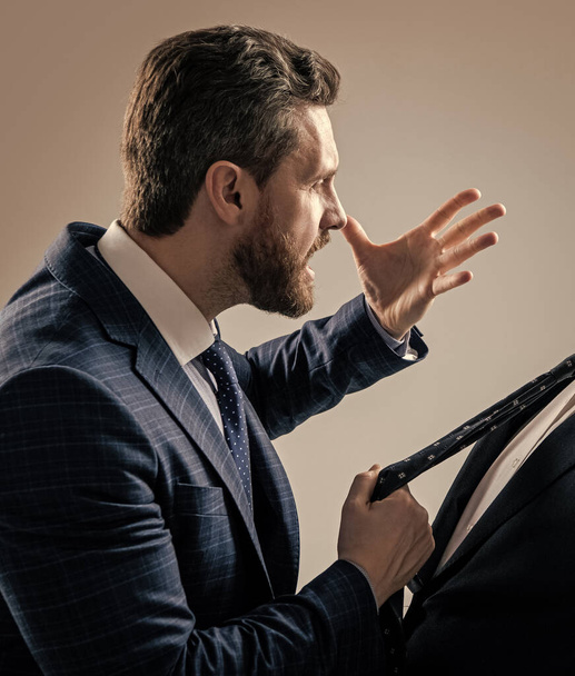 Агрессивный адвокат в костюме делает угрожающий жест тянет человека галстук серый фон, угрожая. - Фото, изображение