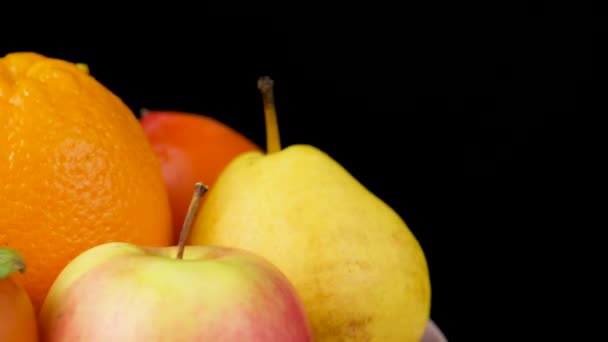 Oranssin ja keltaisen väriset hedelmät - omenat, persimonit, päärynät ja appelsiinit mustalla pohjalla. - Materiaali, video