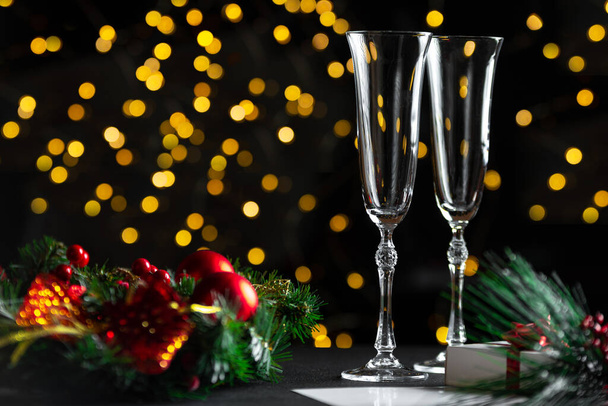 Champagne glazen en bloemenslinger, bokeh op de achtergrond. Gedecoreerde tafel met een nieuwjaarskrans - Foto, afbeelding