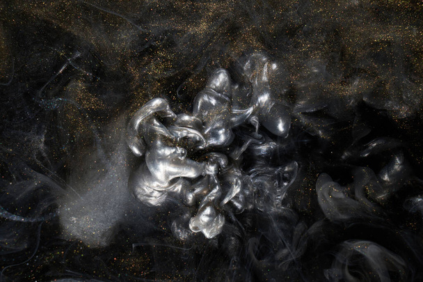 Golden sparkling abstract background, luxury black smoke, acrylic paint underwater explosion, cosmic swirling ink - Foto, Imagem