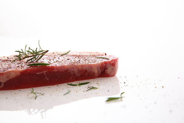"Fresh raw beef steak with pepper and rosemary isolated in white " - Fotografie, Obrázek