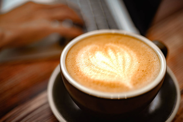 Vista superior de uma xícara de café quente de soja latte art com laptop na mesa de madeira. conceito de mesa de trabalho confortável. - Foto, Imagem