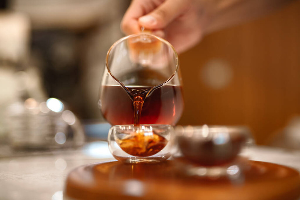 Barista kocht einen Geisha-Kaffee und gießt heißes Wasser aus einem Wasserkocher über ein gemahlenes Kaffeepulver - Foto, Bild