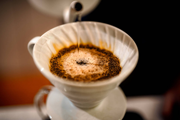 barista ρίχνει ζεστό νερό σε τραχύ καφέ φυσαλίδες καφέ μέσω φίλτρου στάγδην, σπίτι ζυθοποιίας διαδικασία - Φωτογραφία, εικόνα