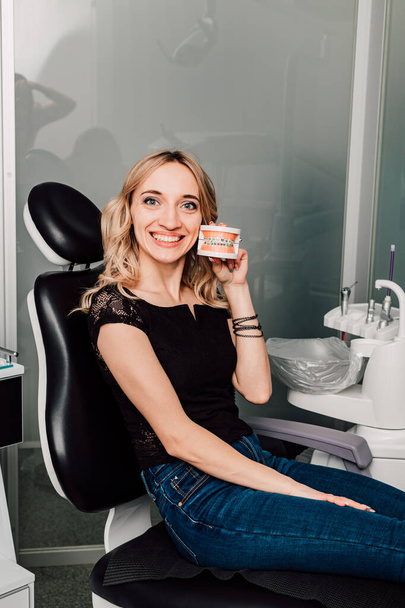 A girl in a dentists chair holds a jaw with braces in her hands. High quality photo - Photo, Image