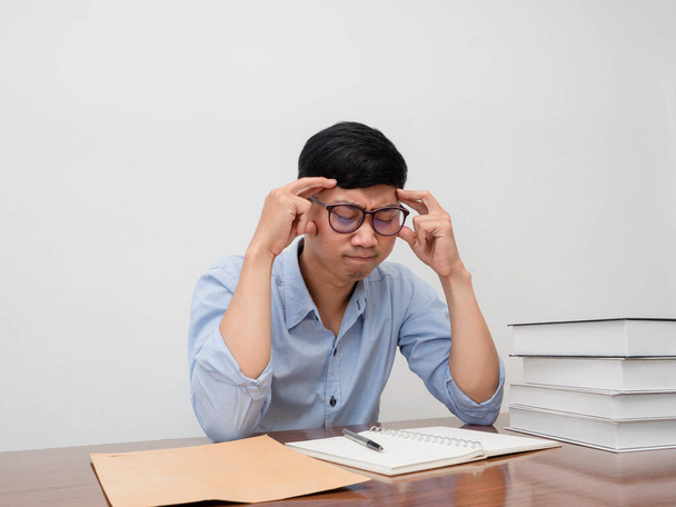 Ασιάτης επιχειρηματίας φοράει γυαλιά κάθεται στο τραπέζι εργασίας κρατήσει το κεφάλι του αισθάνεται δοκιμάσει - Φωτογραφία, εικόνα