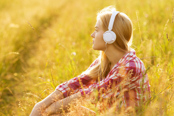 Girl with headphones sitting in the grass - Photo, Image