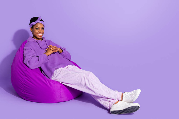 Fénykép vidám pozitív transznemű sit babzsák fényes mosoly viselni fejpánt kapucnis elszigetelt lila színű háttér. - Fotó, kép