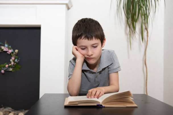 A schoolboy without expressed interest reads a book - Fotoğraf, Görsel