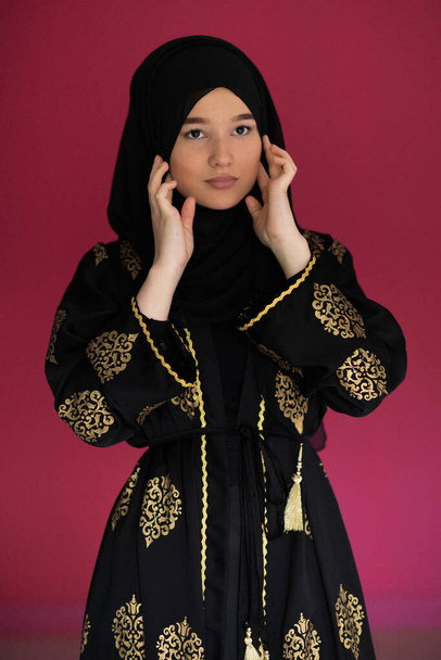 beautiful muslim woman in fashinable dress with hijab isolated on modern red background representing concept of modern islam and ramadan kareem. High quality photo - Фото, зображення