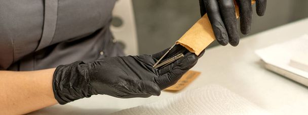 O mestre de manicura tira instrumentos de manicura de um envelope de kraft em um salão de beleza de prego - Foto, Imagem