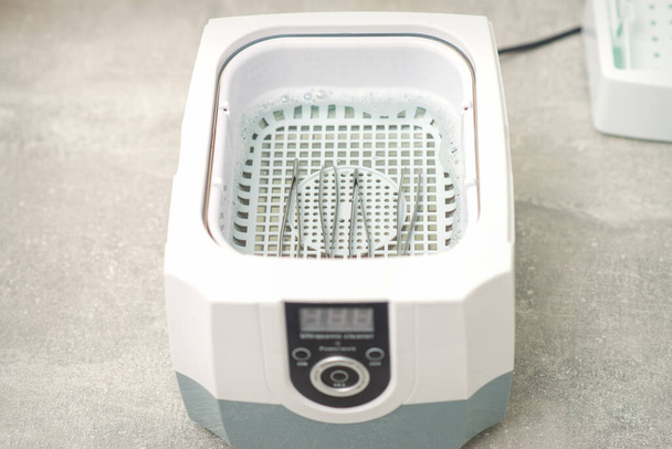 Ультразвуковой инструмент для очистки. Машина для обеззараживания пинцета перед процедурой депиляции - Фото, изображение