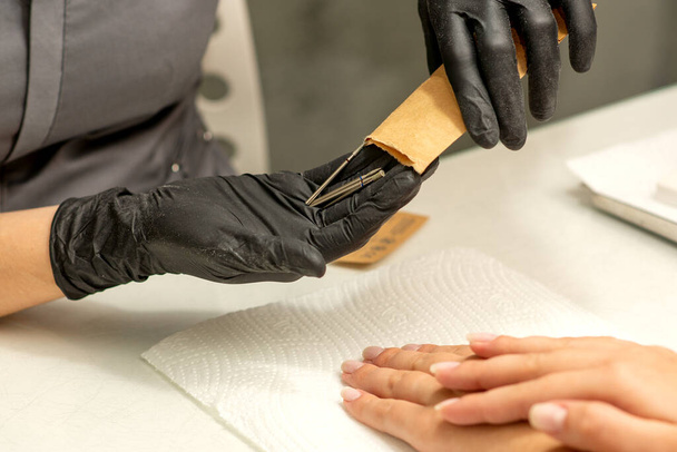 Manikűr mester kiveszi manikűr eszközök egy kraft boríték egy köröm szalon - Fotó, kép