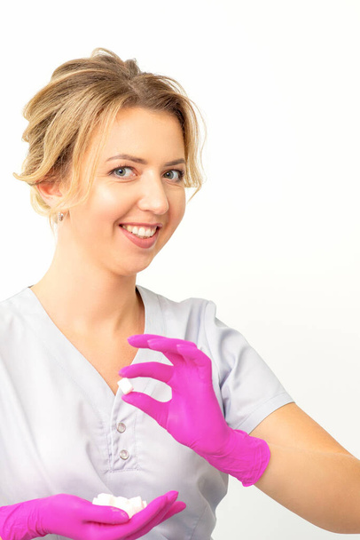 笑顔の若い白人美容師の肖像ピンクの手袋を保持砂糖キューブを示すと白の背景にカメラを見て - 写真・画像