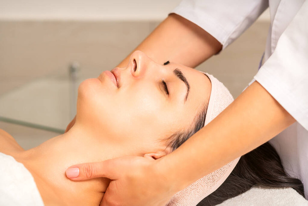 Yüz masajı. Beyaz bir kadın güzellik kliniğinde boynuna masaj yaptırıyor. - Fotoğraf, Görsel
