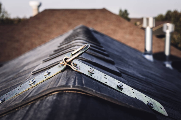 Szelektív fókusz egy fém ideiglenes horgonyra, amelyet a tető tetejére szereltek fel esésvédelem céljából. - Igen. Kiváló minőségű fénykép - Fotó, kép