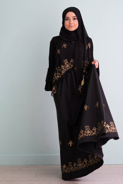 beautiful muslim woman in fashinable dress with hijab isolated on modern cyan background representing concept of modern islam and ramadan kareem. High quality photo - Foto, immagini