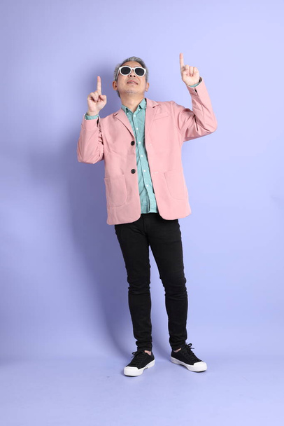 The 40s adult Asian man stnading on the purple background with smart casual clothes. - Foto, imagen