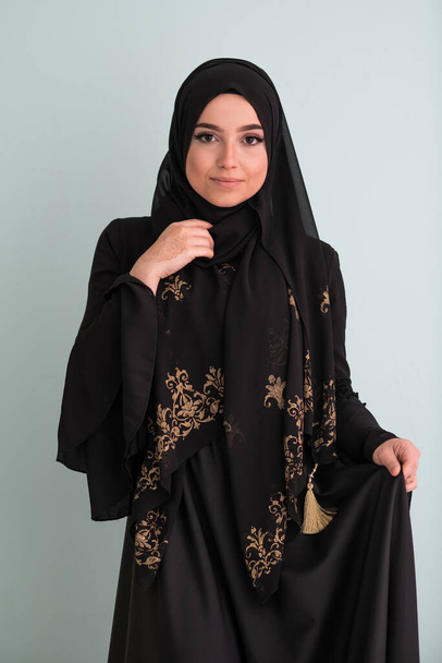 beautiful muslim woman in fashinable dress with hijab isolated on modern cyan background representing concept of modern islam and ramadan kareem. High quality photo - Foto, imagen