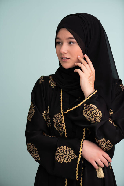 beautiful muslim woman in fashinable dress with hijab isolated on modern cyan background representing concept of modern islam and ramadan kareem. High quality photo - Foto, Imagem