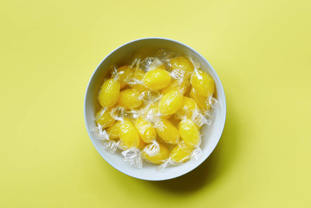 вид сверху на лимонные шоколадные конфеты в миске на желтый цвет , - Фото, изображение