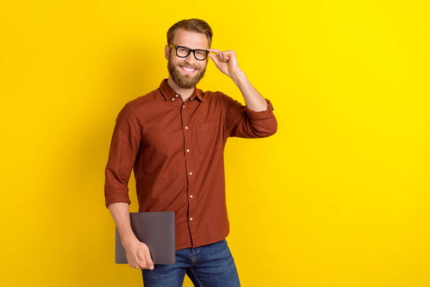 Portrait of good mood man with masculine beard dressed burgundy shirt hold laptop touch glasses isolated on yellow color background. - Fotografie, Obrázek