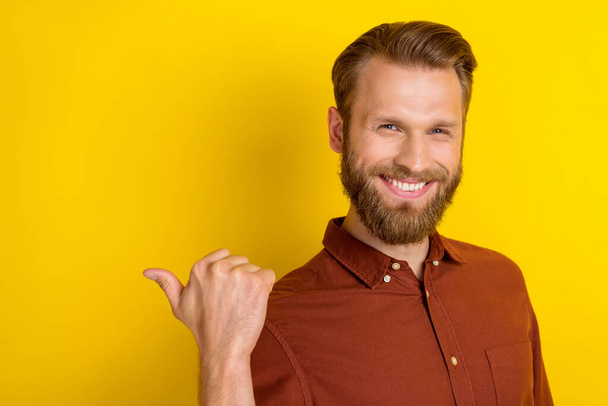 Portrait of cunning tricky funny man with masculine beard wear burgundy shirt indicating empty space isolated on yellow color background. - Fotografie, Obrázek