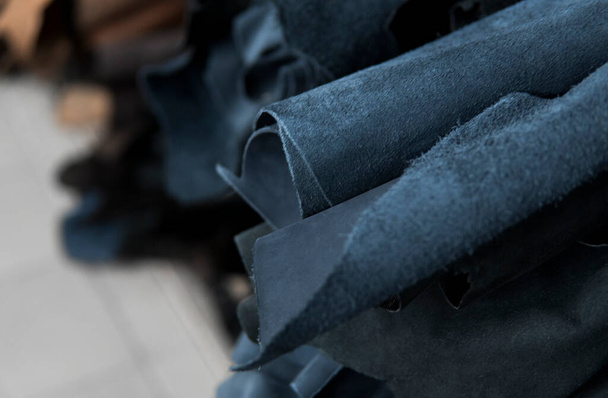 Different pieces of leather in a rolls. The pieces of the colored leathers. Rolls of blue and black leather. Raw materials for manufacture of bags, shoes, clothing and accessories - 写真・画像