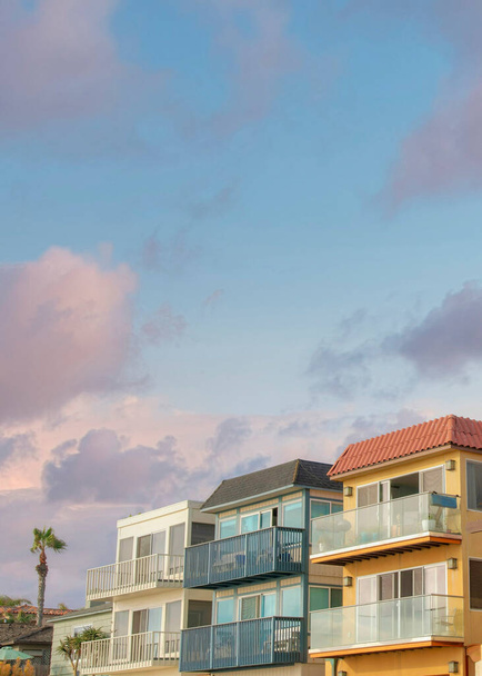 Vertikální Puffy mraky při západu slunce Okolní obytné budovy v La Jolla, Kalifornie. Na pravé straně je paluba s betonovými dlaždicemi baldachýn v blízkosti budov s posuvnými skleněnými dveřmi - Fotografie, Obrázek