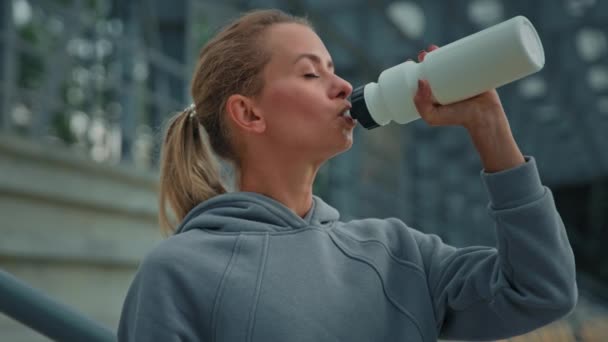 Yorgun bayan sporcu atletik beyaz kız koşucu genç spor model kadın stadyum vücut bakımı hidratında spor üstüne enerji için sağlıklı içecekler içiyor. - Video, Çekim