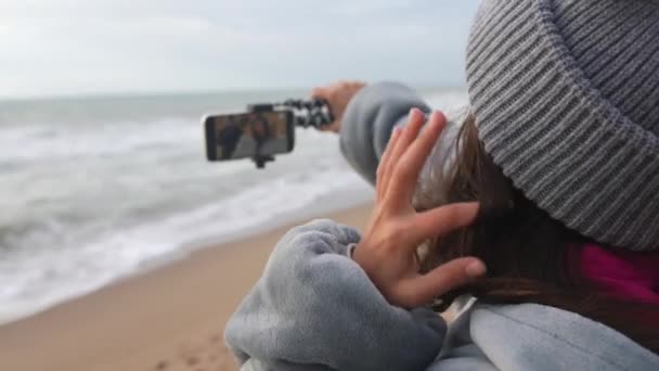 Uma mulher está filmando ou fotografando os mares tempestuosos da praia com um telefone celular. - Filmagem, Vídeo