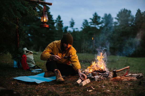 Ένας μοναχικός περιπλανώμενος τρώει στα βουνά δίπλα σε μια φωτιά.. - Φωτογραφία, εικόνα