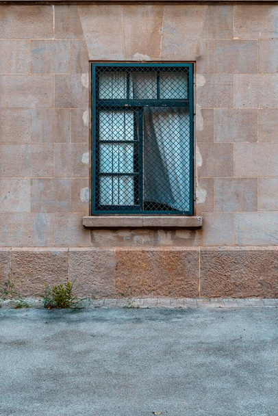 Gevel van een oud huis, IJzeren raam met witte gordijnen wapperend in de wind. - Foto, afbeelding