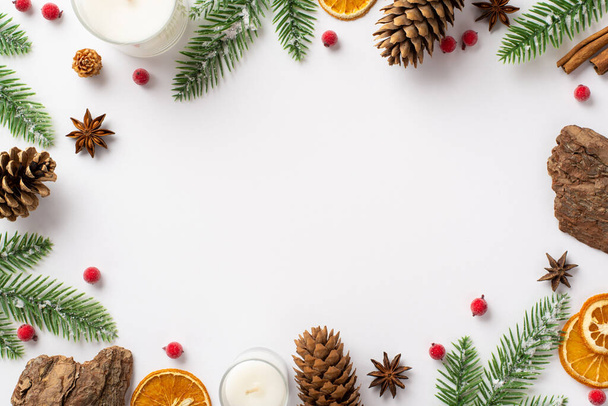 Winter holidays concept. Top view photo of candle pine cones bark fir branches mistletoe berries anise and dried citrus slices on isolated white background with copyspace in the middle - Fotó, kép