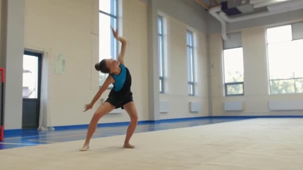 Tornás lány lassított felvételen mutatja be az előadását a táncteremben. Középső felvétel - Felvétel, videó