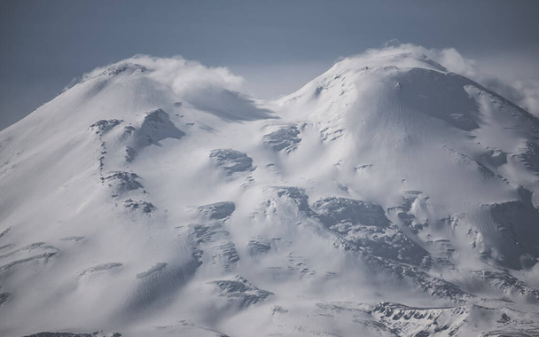 Elbrus hautnah mit Wolken auf den Gipfeln, mit Schnee und Eis, Gletscherrissen mit Eisstücken, bewölkter Herbsttag im Kaukasus - Foto, Bild