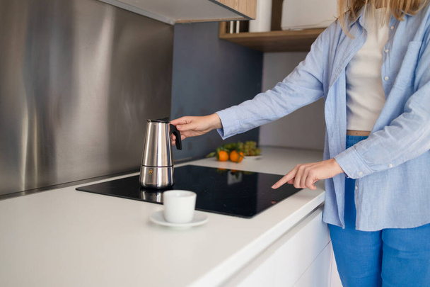 Attraktive Frau in der Küche, die einen Becher heißen Kaffee aus einer Glaskanne gießt. Frühstück am Morgen.  - Foto, Bild