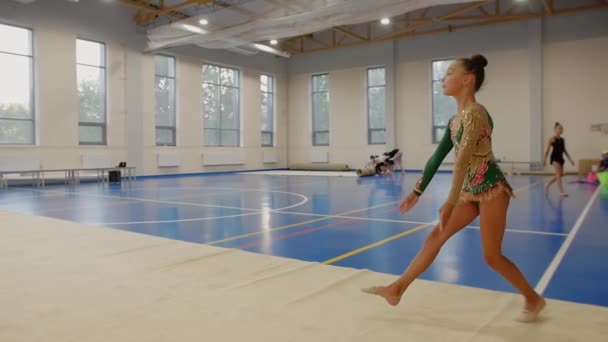 Trening gimnastyczny w hali sportowej - dziewczyna ćwicząca swój występ w zwolnionym tempie. Środek strzału - Materiał filmowy, wideo